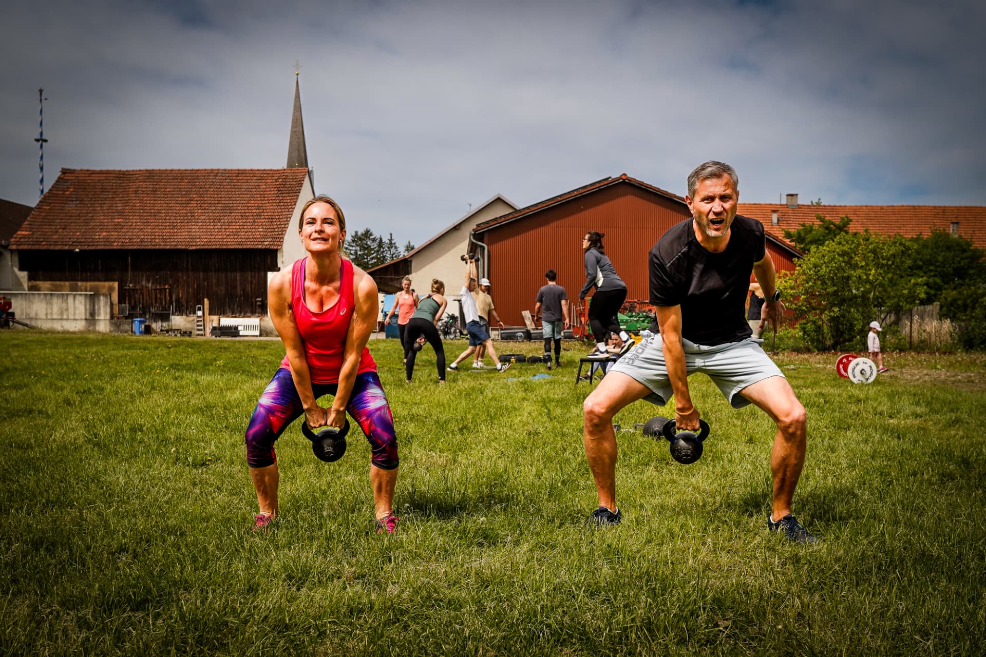 Zwei Teilnehmer beim Kettlebell-Training auf der Wiese