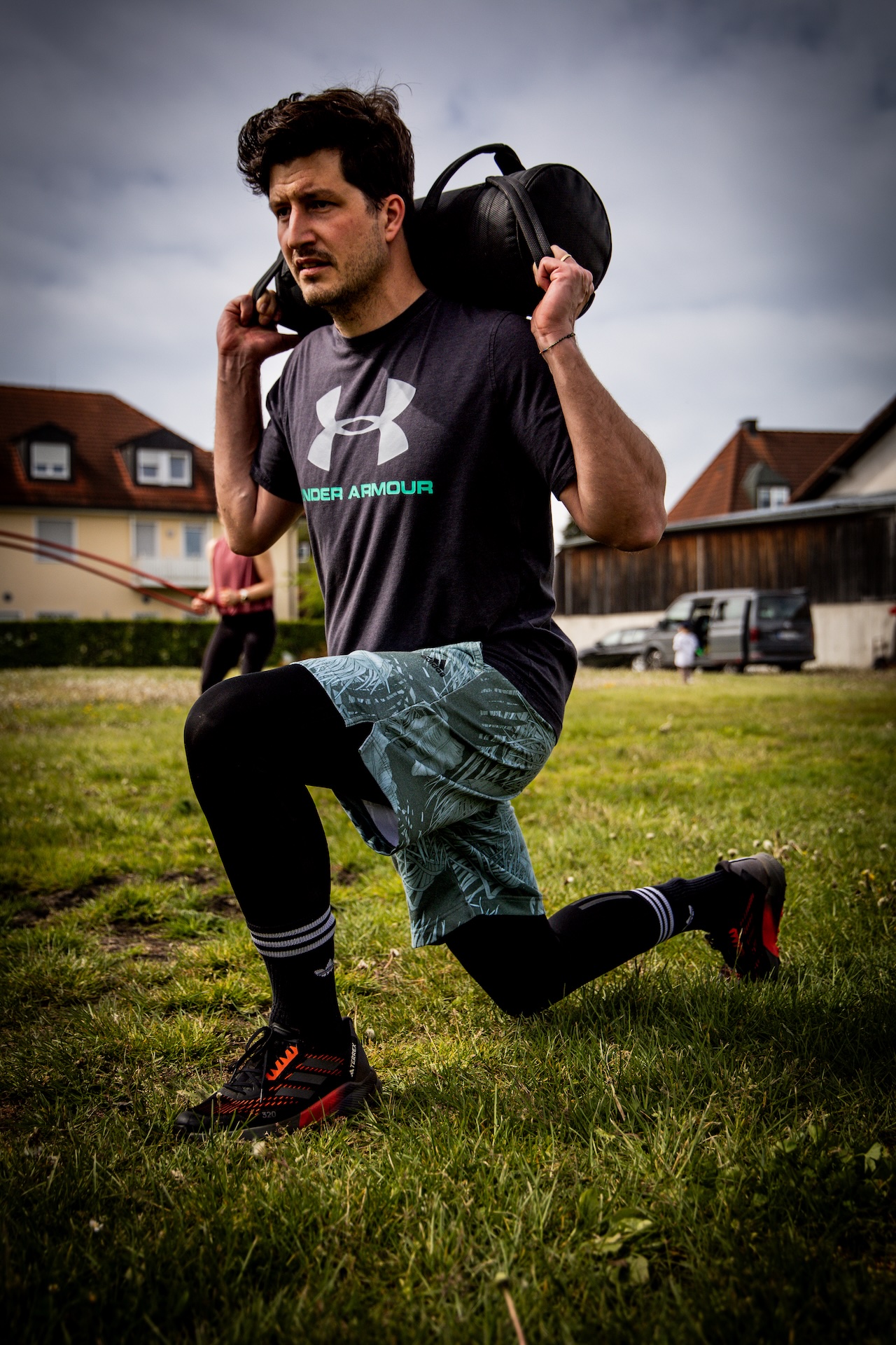 Coach beim Ausfallschritt mit Sandsack auf der Wiese